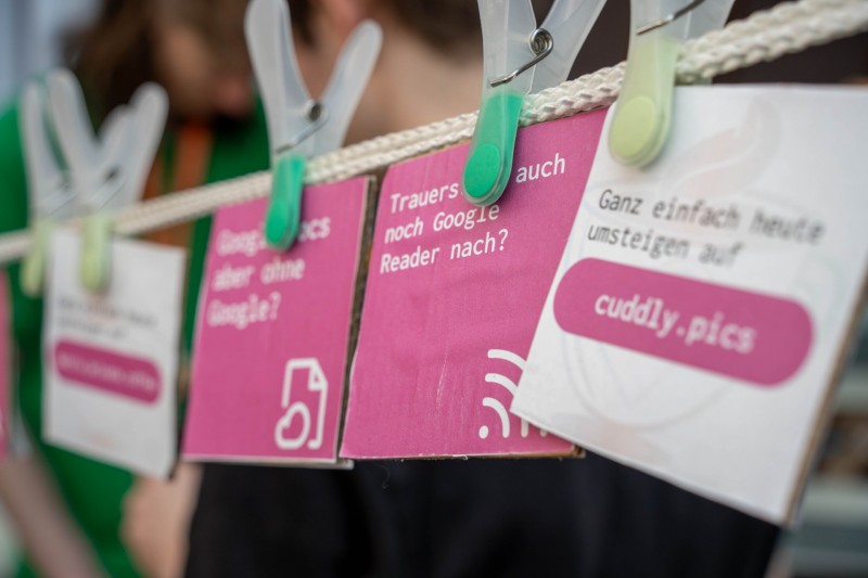 Different services of private.coffee are printed onto a cardboard. One of them reads "trauerst du noch Google Reader nach?" advertising our FreshRSS service.